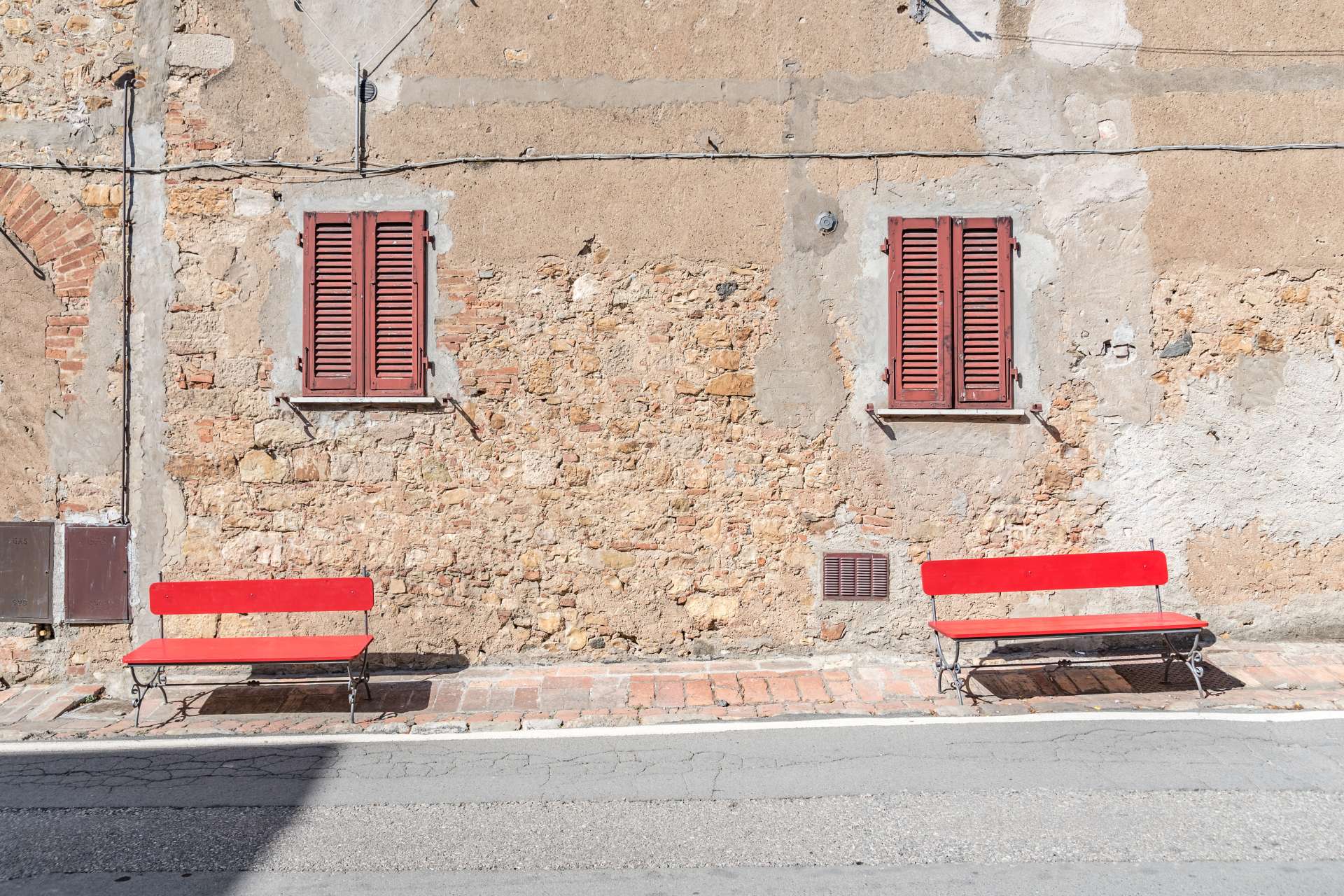 Panchine rosse in una via di Castagneto Carducci